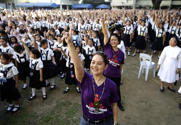 Filipino theater artist Monique Wilson flashes the No.1 sign with students from St. Scholastica`s College, an all-girls` school, as they dance at their campus in a global kickoff campaign dubbed One Billion Rising, to end violence against women and children on Valentine`s Day.