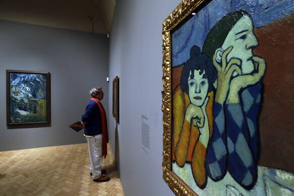 Members of the press walk through a gallery as an oil on canvas 1901 Pablo Picasso painting entitled `Harlequin and Companion` is seen, during a press view of an exhibition in central London.
