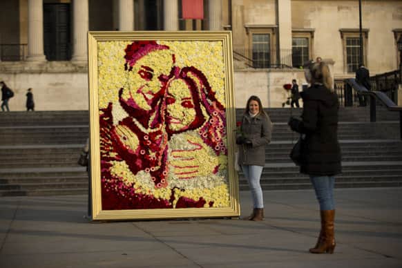 Tourists pose for photographs beside a floral portrait of the Duke and Duchess of Cambridge by British florist Joseph Massie during a promotional display for the media to coincide with Valentine`s Day tomorrow, in Trafalgar Square, London.