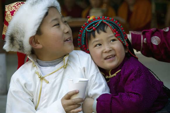 Exiled Tibetan children, in traditional attire, react during a special morning prayer session on the third and one of the most important days of the Tibetan New Year in Dharmsala.