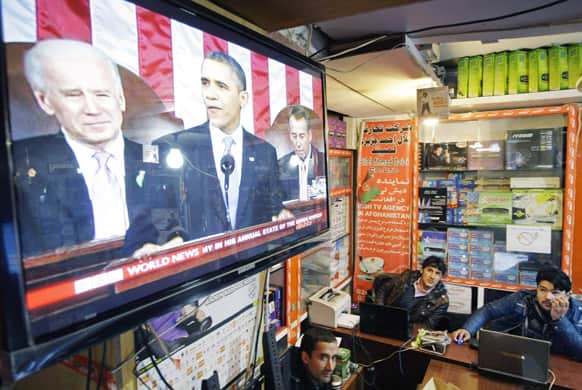 Afghan men watch a television news report on US President Barack Obama`s State of the Union address in Kabul. President Obama announced plans to withdraw more troops from Afghanistan and take steps to boost the fragile US economy.