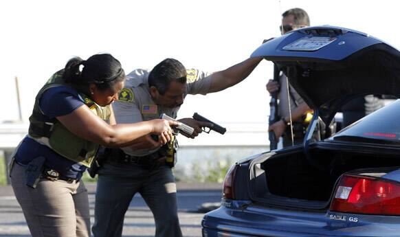 Law enforcement officers check a vehicle at a roadblock near Big Bear, Calif. A man police believe to be the fugitive ex-Los Angeles officer wanted in three killings was barricaded inside a burning cabin Tuesday after a shootout in this California mountain town that left one deputy dead and another wounded.