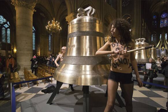 Activists of the Women`s Movement FEMEN, sounds one of the bells ordered for the cathedral`s 850th birthday, in Notre Dame Cathedral, Paris, in protest against the Pope Benedict XVI who announced his resignation yesterday.