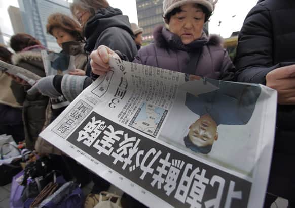 A woman reads a delivered extra edition of a Japanese newspaper reporting North Korea`s nuclear test, in Tokyo.