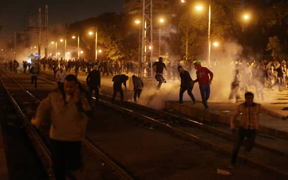 Egyptian protesters run for cover from tear gas fired by riot police, not seen, during clashes next to the presidential palace in Cairo.