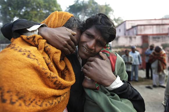 A man whose two relatives died in a stampede at a railway station cries and comforts other relative as they arrive to take the bodies from a morgue, in Allahabad.