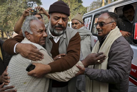 A man whose wife died in a stampede at a railway station, is comforted as he tries to arrange for the release of her body at a local morgue in Allahabad.