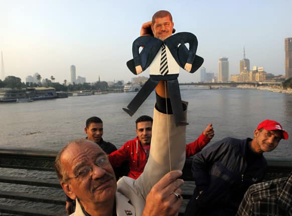 Egyptian artist Mohammed Darwish poses for a photograph with a puppet of Egyptian Islamist President Mohammed Morsi during an anti-Muslim Brotherhood protest on Qasr El-Nile Bridge, crossing the Nile river, in Cairo, Egypt.