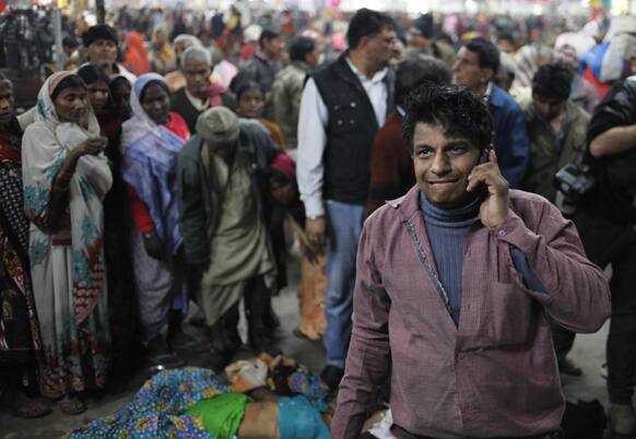An Indian man talks on the phone next to the body of his relative who was killed in a stampede on a railway platform at the main railway station in Allahabad. At least ten Hindu pilgrims attending the Kumbh Mela were killed and more then thirty were injured in a stampede on an overcrowded staircase.