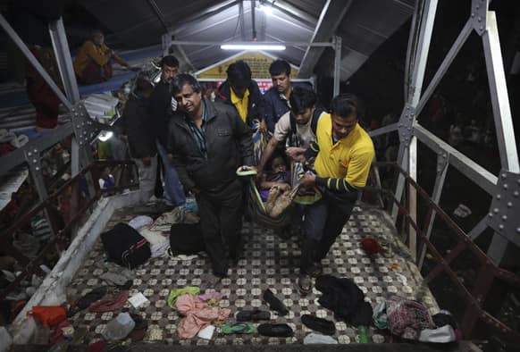 Indian men carry the body of a woman killed in a stampede on the railway platform where the incident occurred at the main railway station in Allahabad.