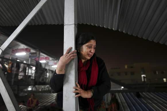 An Indian woman weeps as she watches from a staircase as rescue workers tend to the bodies of those killed in a stampede on a railway platform at the main railway station in Allahabad.