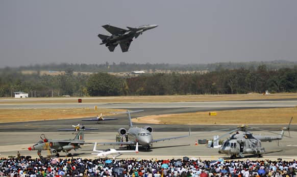 Visitors watch as Tejas, an Indian Air Force light combat aircraft flies over other aircraft on display, on the last day of the Aero India 2013 at Yelahanka air base in Bangalore.