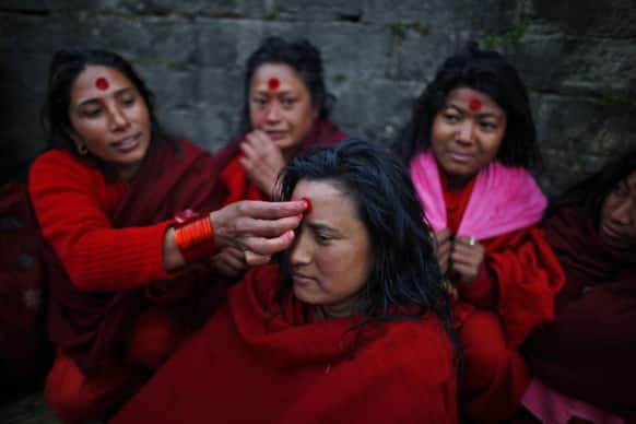 A Nepalese Hindu woman gets vermilion powder applied on her forehead after taking holy dips at the Bagmati River during Madhav Narayan festival in Katmandu, Nepal.