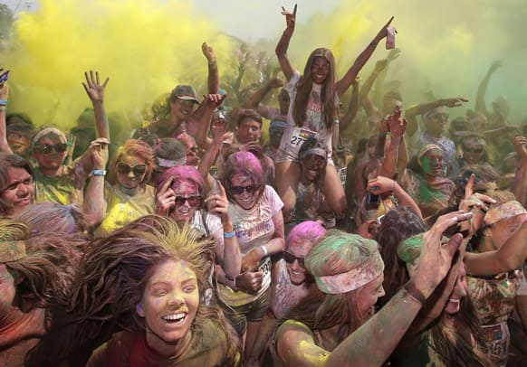 People celebrate and dance in clouds of colored dust after the Swiss Color Run at Homebush Olympic Park in Sydney, Australia. The Color Run is a 5K feel good, happy event that sees participants go through a “color station” every kilometer where they are covered with colored powder.