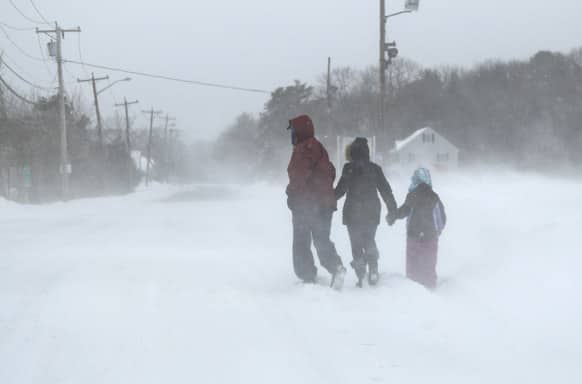 Pedestrians make their way down a road during whiteout conditions in Salisbury, Mass. A behemoth storm packing hurricane-force wind gusts and blizzard conditions swept through the Northeast, dumping more than 2 feet of snow on New England & knocking out power to 650,000 homes & businesses.