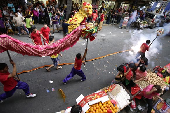 Firecrackers explode as dragon dancers perform in front of Chinese business establishments on the eve of Chinese New Year celebration at Manila`s Chinatown district of Binondo in Manila, Philippines.