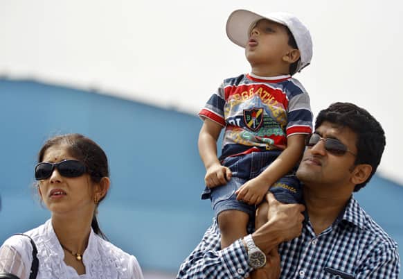 A family watches a performance by a fighter aircraft on the third day of the Aero India 2013 at Yelahanka air base in Bangalore.