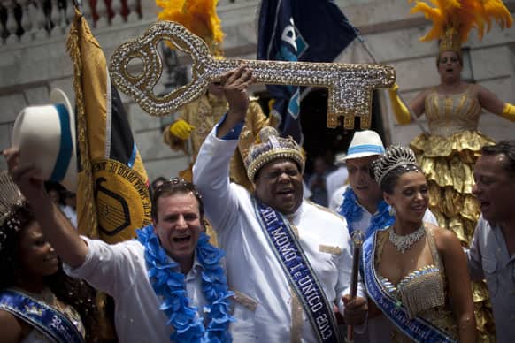 The mythical jester figure who reigns over Carnival, this year`s King Momo; the crowned and costumed Milton Rodrigues Junior, center, holds up the key of the city that was given by Rio de Janeiro`s Mayor Eduardo Paes, left, at the official ceremony kicking off the five-day bash, in Rio de Janeiro, Brazil.