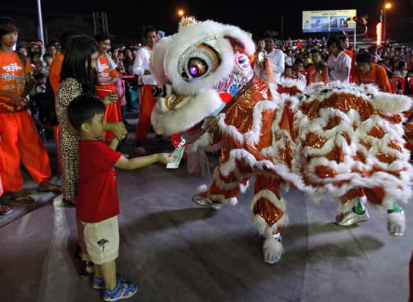 Myanmar Chinese boy offer paper money to a traditional Lion dancer during an event marking incoming Lunar New Year, at a shopping mall in Yangon, Myanmar.