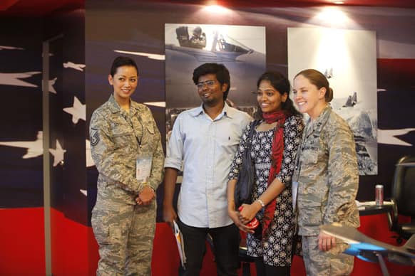 Visitors pose with US Air Force officials at their booth on the second day of the Aero India 2013 at Yelahanka air base in Bangalore.