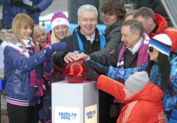 Moscow`s Mayor Sergei Sobyanin, center, surrounded by various officials, sport enthusiasts and entertainers hits a symbolic button to launch the one-year count down clock for the upcoming 2014 Sochi Olympics, in Moscow.