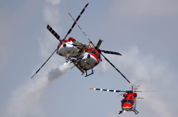 Indian Air Force helicopters cross paths while performing an aerobatic flight on the opening of the Aero India 2013 at Yelahanka air base in Bangalore.