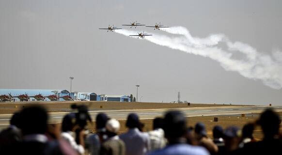 Journalists watch the Flying Bulls Zlin 50LX single-engine and single-seater aerobatic display team from the Czech Republic perform on the opening of the Aero India 2013 at Yelahanka air base in Bangalore.