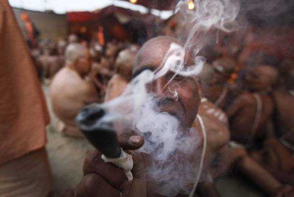 Hindu holy men of the Juna Akhara sect smokes tobacco in between a rituals that are believed to rid them of all ties in this life and dedicate themselves to serving God as a