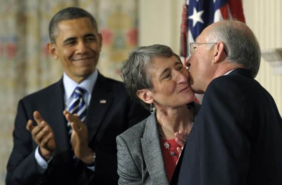 President Barack Obama watches as his Interior Secretary nominee, REI Chief Executive Officer Sally Jewell, center, gets a kiss from outgoing Interior Secretary Ken Salazar, in the State Dining Room of the White House in Washington, where the president announced that Jewell is his choice to replace Salazar.