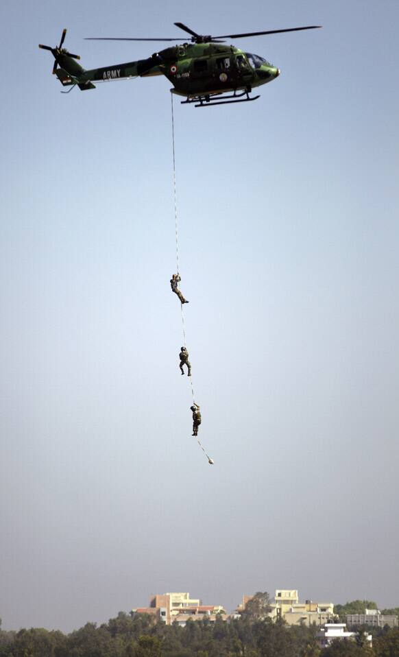 Indian army personnel come down from a chopper to show their skills during the opening of the Aero India 2013 at Yelahanka air base in Bangalore.