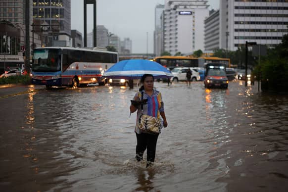 A woman walks on a flooded street following a heavy rain at the main business district in Jakarta, Indonesia.