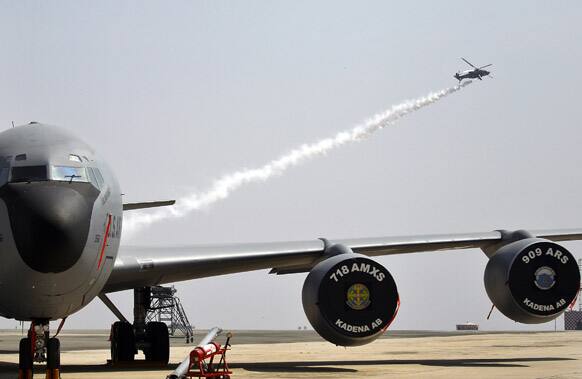 An Indian helicopter flies over a U.S. Air Force KC-135 during rehearsals on the eve of the Aero India 2013 at Yelahanka air base in Bangalore.