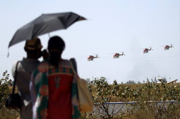A couple watches Indian Air Force helicopters perform formation flight during rehearsals ahead of the Aero India 2013 in Yelahanka air base in Bangalore.