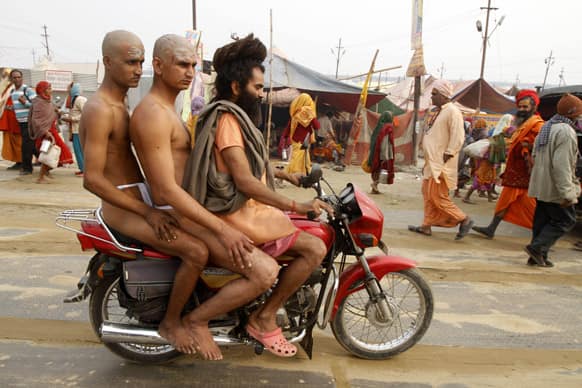 Two Hindu holy men of the Juna Akhara are being taken on a motorcycle by their teacher at Sangam during the Maha Kumbh festival in Allahabad.