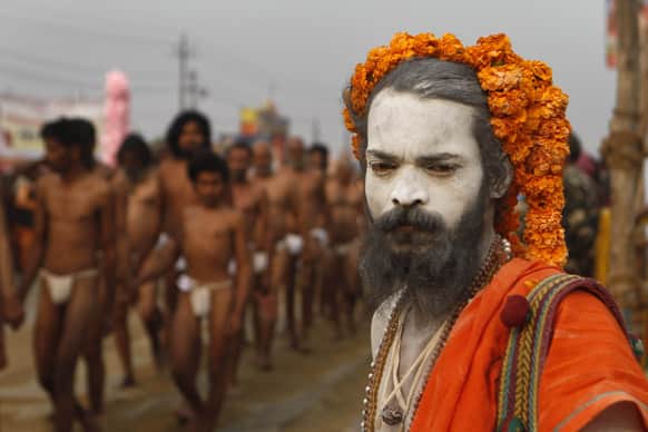 A Naga Sadhu watches as Hindu holy men of the Juna Akhara sect arrive for a rituals that are believed to rid them of all ties in this life and dedicate themselves to serving God as a `Naga` or naked holy men, at Sangam during the Maha Kumbh festival in Allahabad.