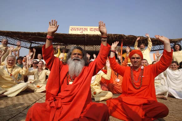 Chief priest of Mahanirvani Akhara, Swami Maheshwaranand Puri with his foreign devotees shout slogans after consecration ceremony at Sangam, the confluence of rivers Ganges, Yamuna and mythical Saraswati, during the Maha Kumbh festival, in Allahabad.