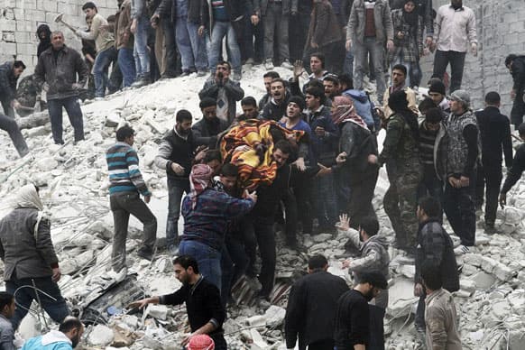 Syrian people carry a body after a government airstrike hit the neighborhood of Ansari, in Aleppo, Syria.