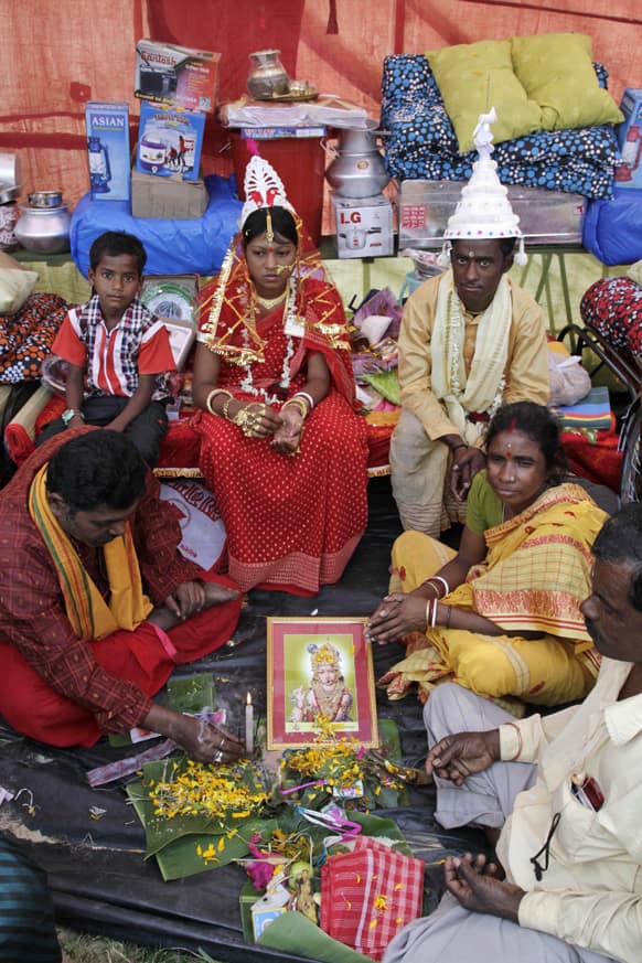 A couple, background, sits as their elder relatives perform a ritual a mass community marriage in Bahirkhand, about 70 kilometers (44 miles) north of Kolkata.