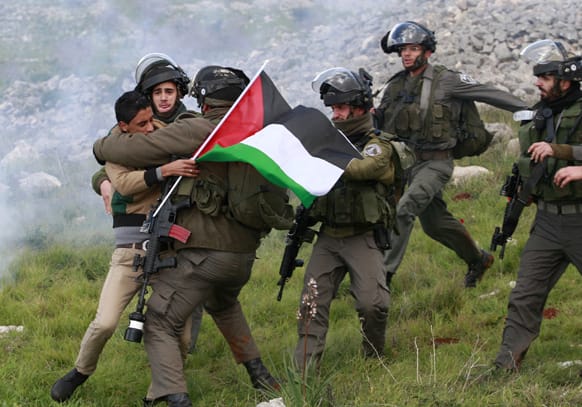 Israeli security forces detain a Palestinian activist during a protest against Jewish settlements near the West Bank village of Burin.