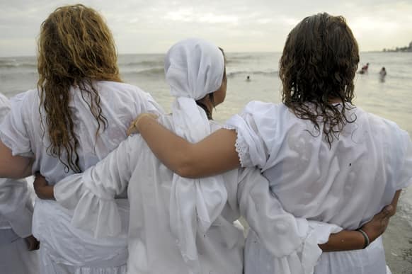 Faithful stand arm in arm after delivering their offerings to Yemanja, the African sea goddess, in Montevideo, Uruguay.
