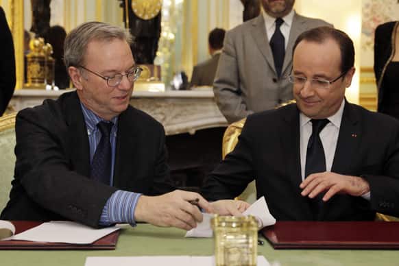 Google CEO, Eric Schmidt, left, and French President Francois Hollande sign an agreement at the Elysee Palace in Paris.