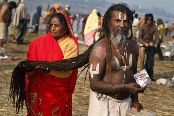 Bhola Das, right, shows a photo of his guru as his wife Durga Devi keeps him dry his hair during the Maha Kumbh festival.