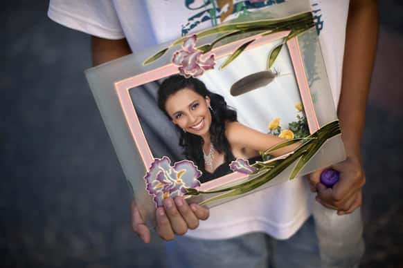 A youth holds a photograph of his sister Pamella Lopes, who died in a nightclub fire, in a public square near the club in Santa Maria, Brazil.