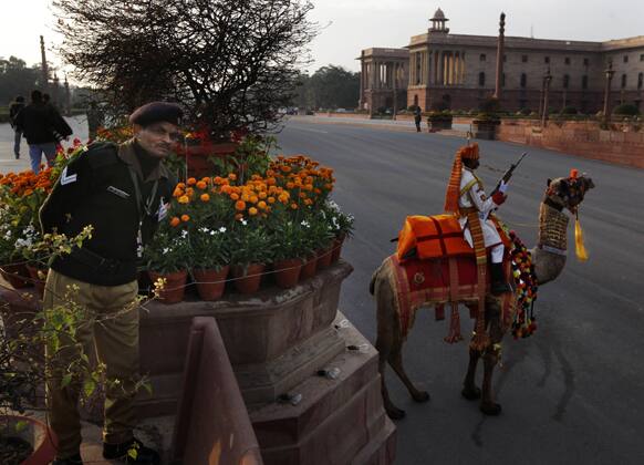A security person, left, watches as a camel mounted Indian Border Security Force soldier in his ceremonial dress participates in full dress rehearsals of the Beating Retreat ceremony at Raisina hill which houses India`s most important ministries and presidential palace, in New Delhi.