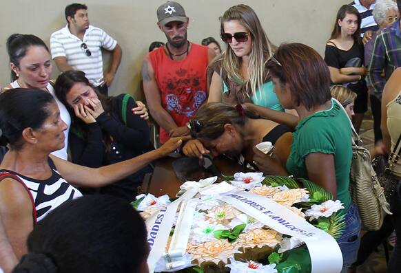 Family members and friends mourn as they stand around a coffin containing the remains of a victim after the bodies were identified at a gymnasium in Santa Maria city, Rio Grande do Sul state, Brazil.