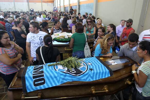 Family members and friends stand around coffins containing the remains of victims after the bodies were identified at a gymnasium in Santa Maria city, Rio Grande do Sul state, Brazil.