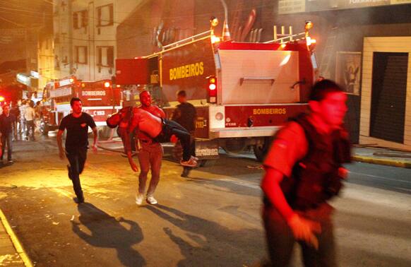 A man carries an injured man, victim of a fire at the Kiss club in Santa Maria city, Rio Grande do Sul state, Brazil.