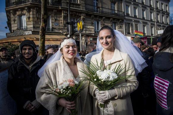 Women pose during a demonstration for the government project to legalize same-sex marriage and adoption for same-sex couples in Paris, France.