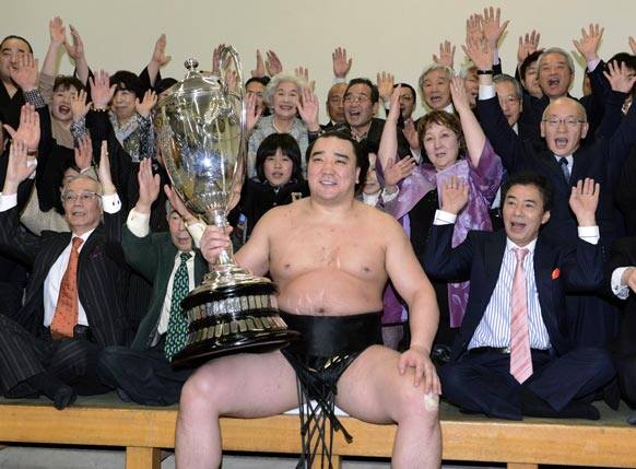 Mongolian grand champion Harumafuji poses with the Emperor`s Cup and cheering supporters for photographers after winning the New Year Grand Sumo tournament in Tokyo.