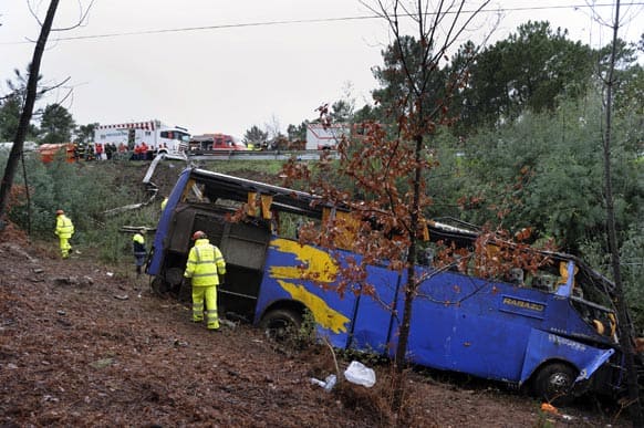 Portuguese firefighters work around the wreckage of a bus which ran off the road and crashed into a ravine, killing 10 people and injuring 33, officials said, in Serta.